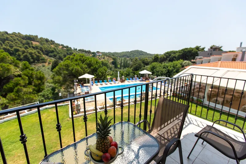 A balcony with fruit on the table, over the pool