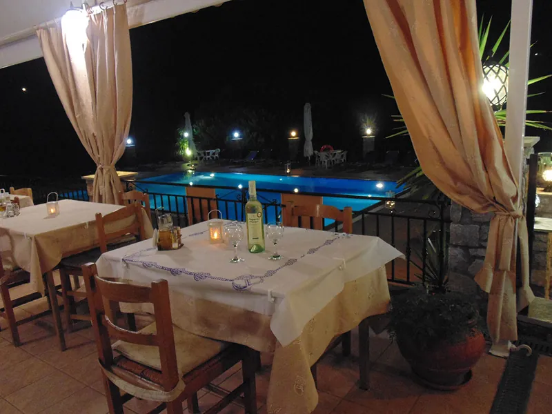 A taverna table by the lit pool at night